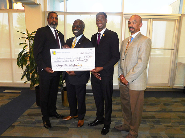 President Armbrister receiving check from members of Omega Psi Phi