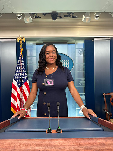 Jayla poses from behind podium in briefing room