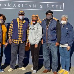 President and Mrs. Armbrister standing with others in front of wall that says Samaritan's Feet