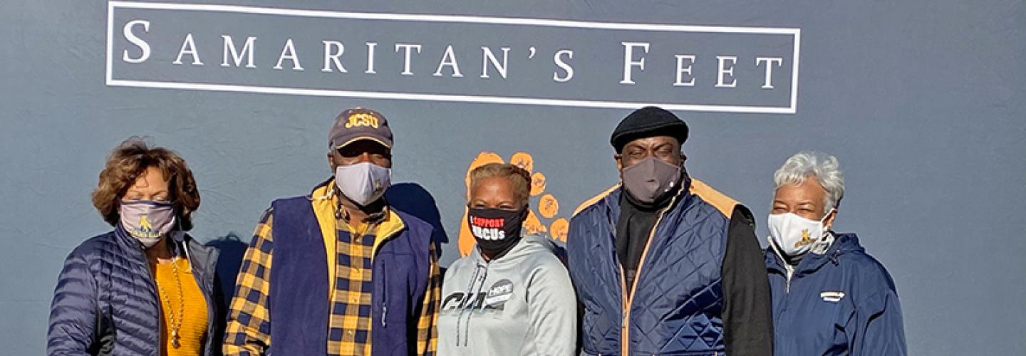 President and Mrs. Armbrister standing with others in front of wall that says Samaritan's Feet