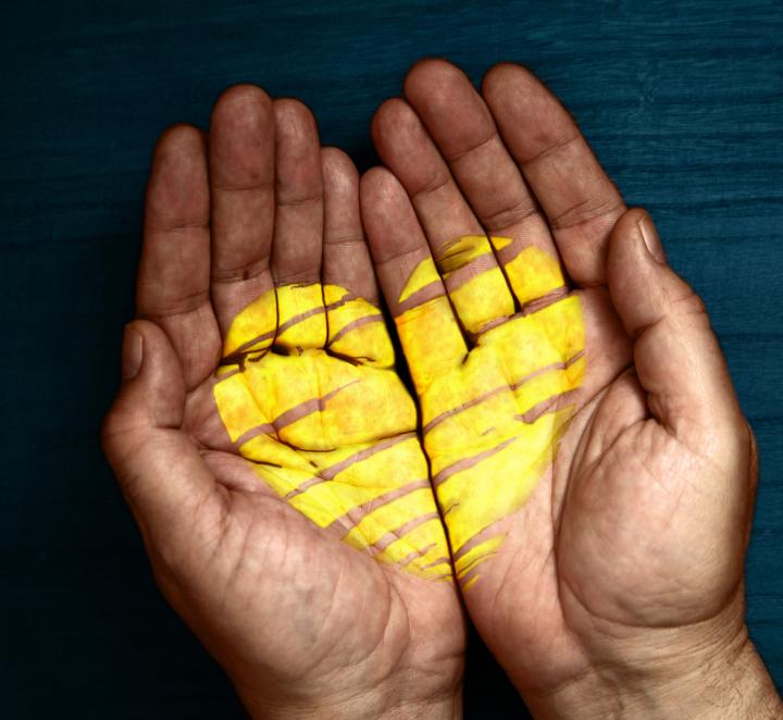 A pair of hands holding aa golden heart