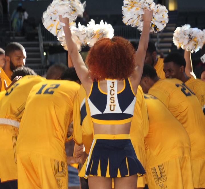 Golden Bulls basketball players in a huddle surrounded by Luv-A-Bull cheerleaders