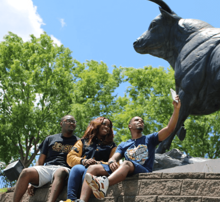 people sitting on a wall near a bull statue