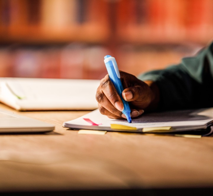 Person's hand highlighting a book in a library