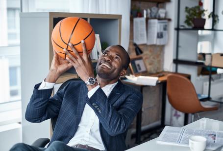 Man in suit behind desk with basketball