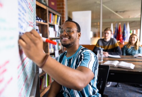 Student at whiteboard with flags in the background