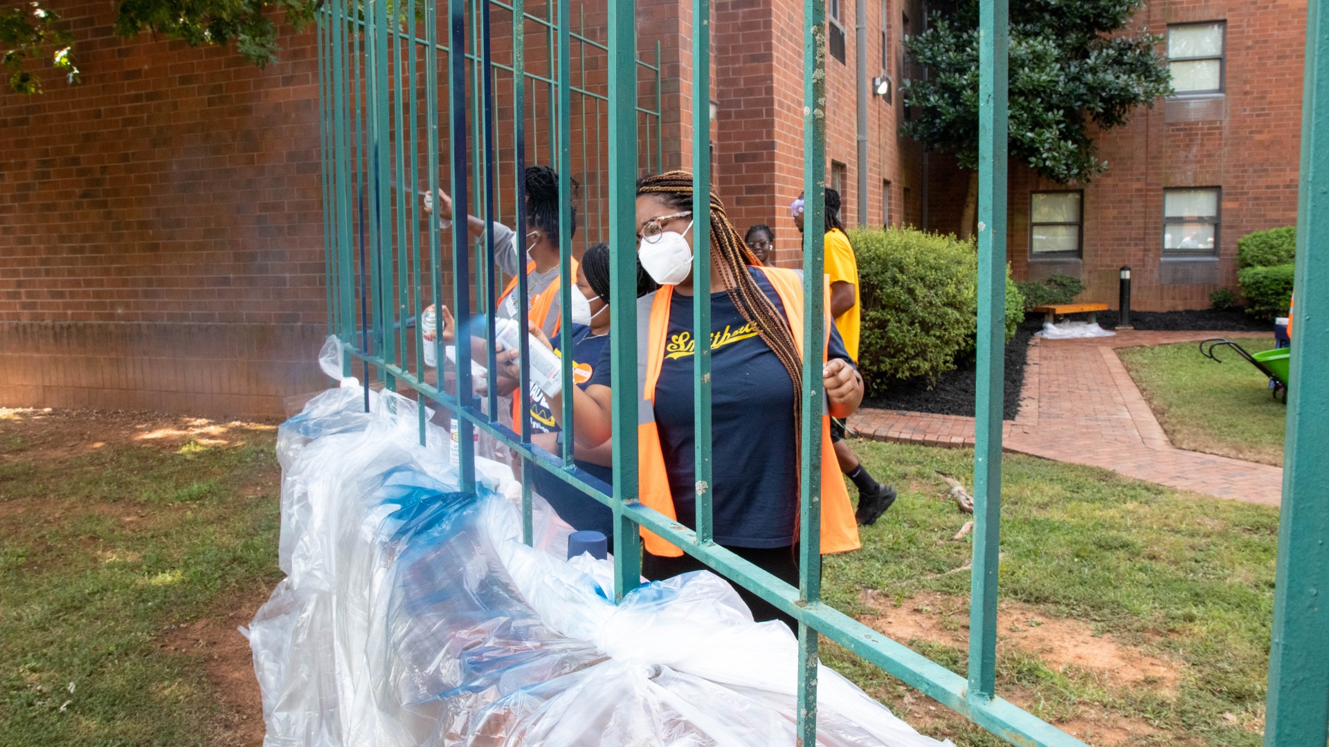 Student volunteers spray painting over the outer fence of Greenfield Gardens