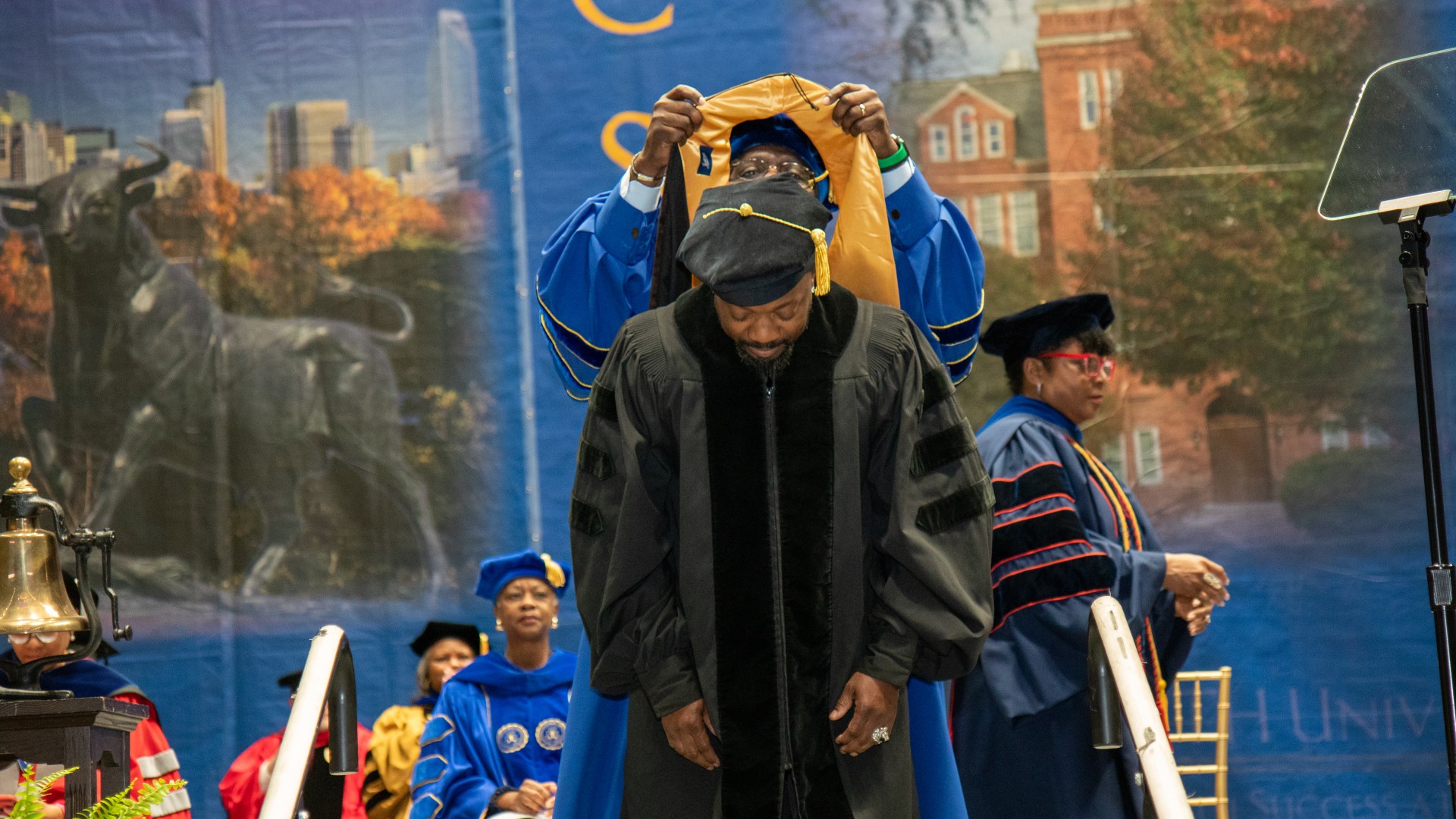 President Clarence D. Armbrister places a hood on Anthony Hamilton
