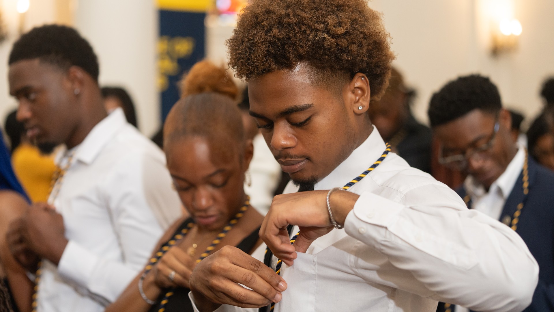 Freshmen place their pins on their shirts during Freshman Convocation 2023