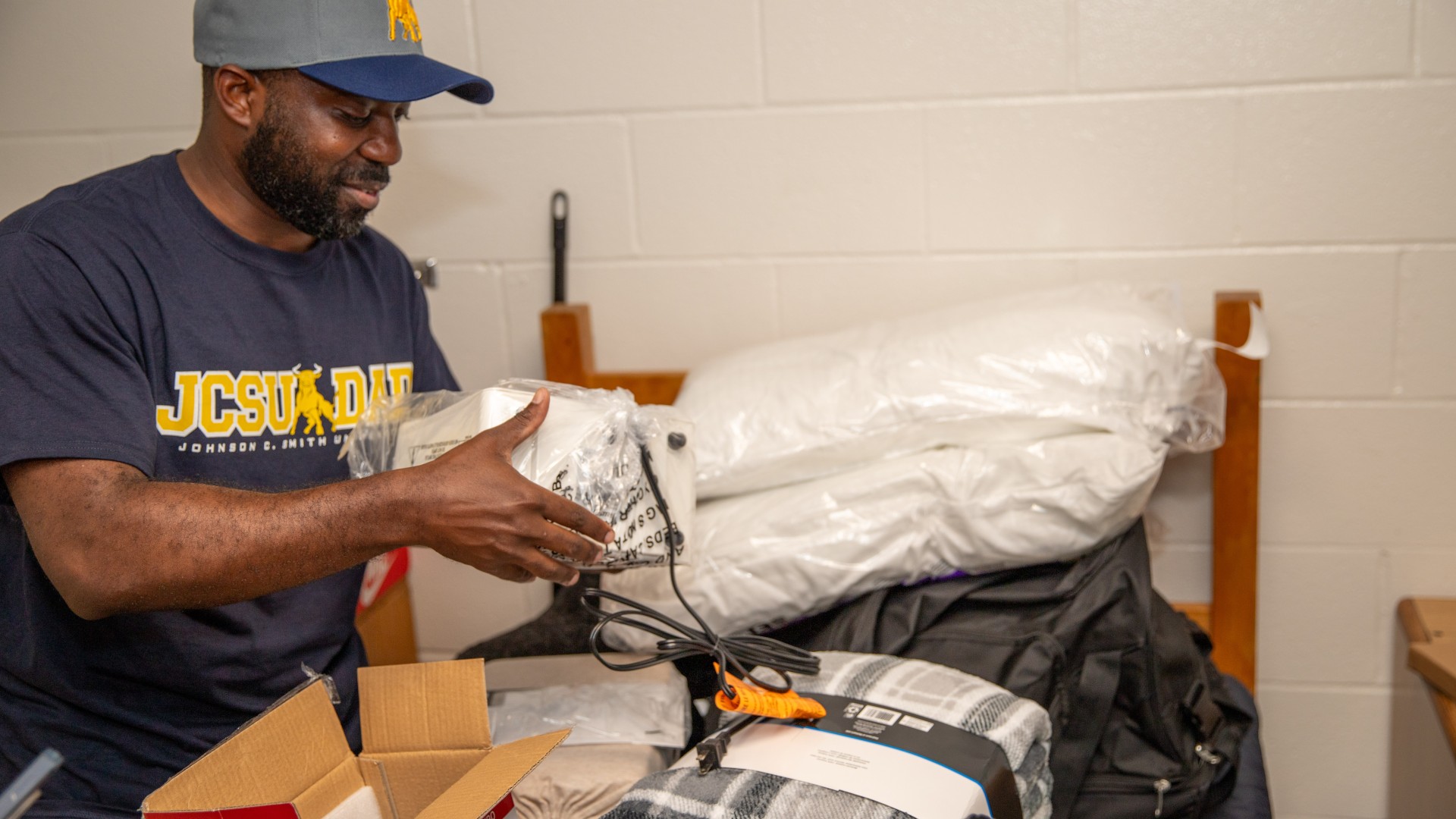 Man unwrapping a fan in Myers Residence Hall during Freshman Move in 2023