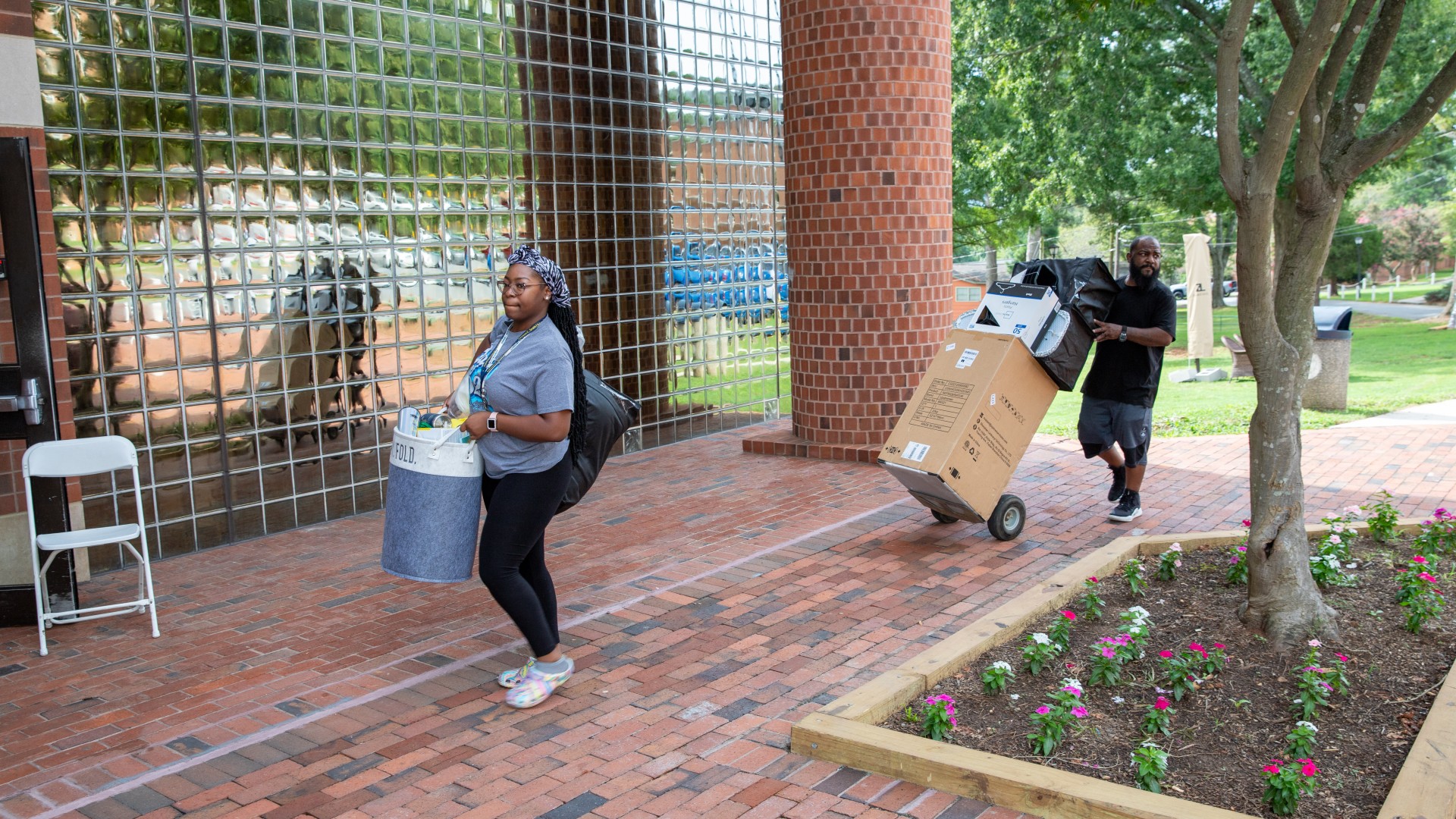 Man and a woman carrying items into Greenfield during Freshman Move in 2023